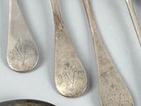 five silver spoons and a silver spoon on a table