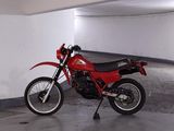 a red motorcycle parked in a parking garage next to a white wall
