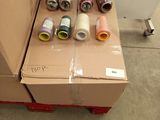 many rolls of thread on a carton in a room