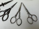 five pairs of scissors sitting on a table next to a pair of scissors