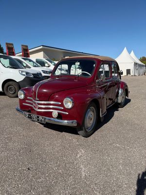 une voiture rouge garée sur un parking, avec d'autres voitures en arrière-plan