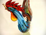 a colorful glass sculpture of a rooster on a clear base