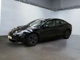the black tesla model 3 is parked in a large room