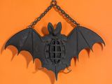 une chauve-souris suspendue à une chaîne sur un mur orange