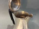 a silver pitcher with a black handle on a table