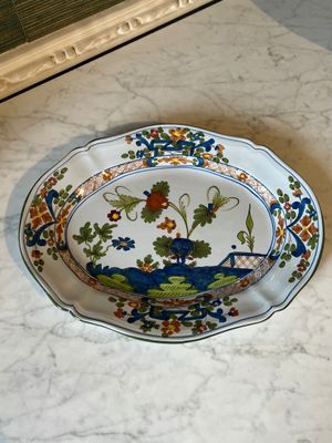 a plate with a peacock on it sitting on a table
