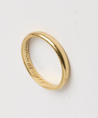 gros plan d'une bague en or sur une surface blanche