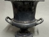 a large metal vase with a handle on it