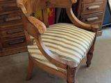 une chaise en bois avec une assise rayée, placée devant une commode