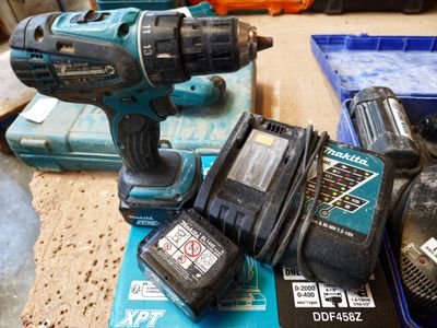 a cordless drill and two batteries sitting on a table