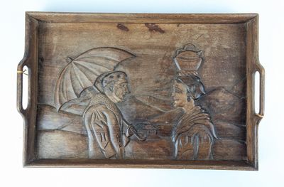 a wooden tray with a carved picture of a man and a woman