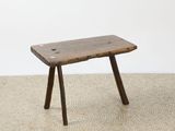 an old wooden bench sitting on top of a floor next to a white wall