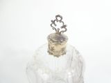 a glass bottle with a silver lid on a white surface