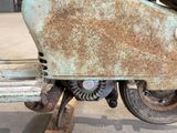 a rusted motorcycle with a wheel on a wooden stand