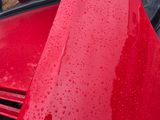 a red car that is parked in the rain