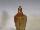 un petit vase brun posé sur une surface blanche
