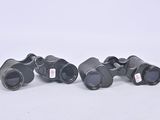 three pairs of black binoculars sitting on top of a white surface