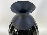 a black vase that is sitting on a white surface