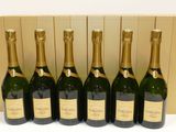 six bouteilles de champagne alignées en rang devant une boîte en carton