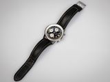 une photo d'une montre posée sur une surface blanche, avec un bracelet noir