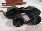 a pair of binoculars sitting on a bed next to a handbag