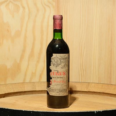 a bottle of wine sitting on top of a barrel