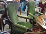 de nombreuses chaises vertes dans une pièce où sont accrochés des tableaux au mur