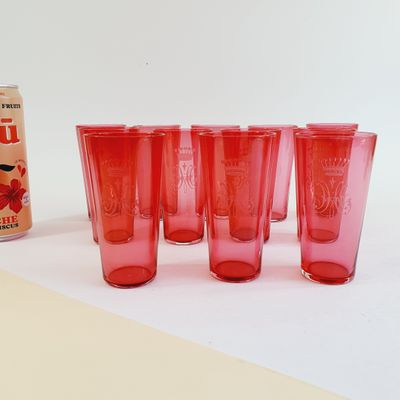 six red glasses and a can of soda on a table