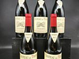 quatre bouteilles de vin rouge sont posées sur une boîte noire