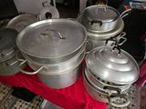 many pots and pans sitting on a red cloth