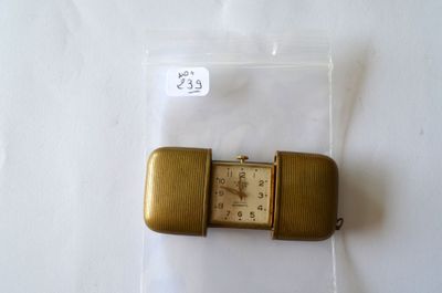 une petite montre en or dans un sachet en plastique, posée sur une surface blanche