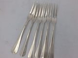 six forks and a knife on a table with a white background