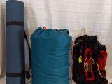 two bags and a backpack on a bed next to each other