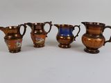 four different sized vases are lined up on a white surface