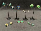 a set of five small green, yellow and blue earrings on black stands