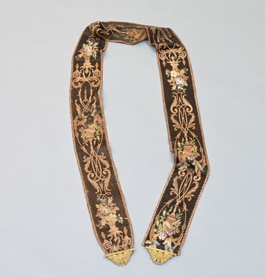 un gros plan d'un collier marron et doré posé sur une surface blanche