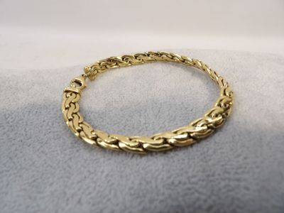 a close up of a gold bracelet on a white surface