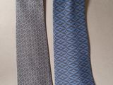 pair of two neck ties on a table with a white background