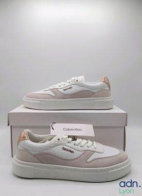une paire de baskets blanches et roses posée sur une boîte blanche