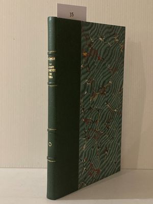 un vieux livre à la couverture verte posé sur une table blanche