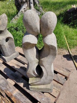 trois sculptures en pierre posées sur une palette près d'un arbre