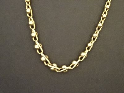 un gros plan d'un collier à chaîne en or porté par un mannequin