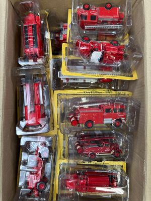une boîte remplie de petits camions de pompiers rouges