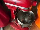 un mixeur rouge posé sur une table en bois, à côté d'un chapeau orange