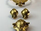 three pieces of gold jewelry sitting on top of a white surface