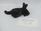 a black cat sitting on top of a table next to a piece of paper