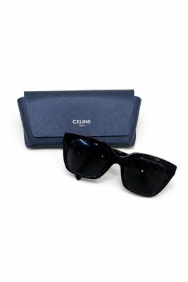 Les lunettes de soleil sont noires et sont accompagnées d'un étui bleu.