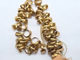 bracelet plaqué or avec des clochettes et une étiquette sur fond blanc