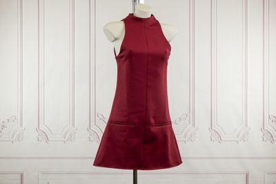 the red dress is on a mannequin stand in front of a white wall