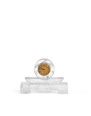 une horloge en verre posée sur un socle en marbre